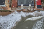 La indignació veïnal i la preocupació pel futur de la costa han tornat a prendre el passeig marítim de Tavernes de la Valldigna en una nova jornada de protestes. Centenars de residents s'han mobilitzat per a exigir a la Direcció General de Costes la regeneració urgent del seu litoral, greument afectat per la pèrdua d'arena i l'amenaça directa del mar sobre els habitatges. TAVERNES DE LA VALLDIGNA. 23 d'agost de 2026.— El malestar veïnal i la preocupació mediambiental han tornat a prendre els carrers de Tavernes de la Valldigna. Centenars de residents s'han mobilitzat aquest cap de setmana per a alçar la veu davant el que consideren una situació insostenible: la paulatina i imparable desaparició del seu front litoral a causa dels successius temporals marítims que afecten la zona. La pèrdua de superfície de platja ha aconseguit nivells sense precedents en el municipi. Segons els últims informes tècnics i mesuraments locals, algunes seccions de la costa han perdut fins a un 77% de la seua massa d'arena original, deixant el ferm de les zones habitades exposat a l'embat directe de l'onatge. Habitatges en perill i desallotjaments preventius La gravetat de l'erosió ha deixat de ser una mera pèrdua d'atractiu turístic per a convertir-se en un problema de seguretat pública. Els últims episodis de marejada i fort onatge van provocar l'esfondrament de murets de protecció i la infiltració d'aigua en les infraestructures costaneres, una situació que va obligar les autoritats locals a evacuar d'emergència diversos habitatges situats en primera línia de mar. Els propietaris afectats denuncien que la falta d'arena ha après el matalàs natural que abans amortia la força de les ones, deixant les fonamentacions directament exposades a la violència de la mar. Exigències a les administracions i silenci municipal La marxa pacífica va recórrer el passeig marítim exigint solucions definitives a la Direcció General de Costes i al Ministeri per a la Transició Ecològica. Els col·lectius veïnals reclamen superar la fase dels "parches d'emergència" —basats en l'aportació puntual d'arena que els temporals tornen a arrossegar— i executar projectes d'enginyeria de regeneració litoral duradors, com ara la instal·lació d'espigons o barreres submarines. Per la seua banda, el govern local ha evitat fer cap mena de publicitat de la convocatòria. Aquesta actitud manté la línia de l'alcaldessa, de signe socialista, qui igual que va evitar enfrontar-se amb el ministre Óscar Puente per a exigir la represa de les obres de l'estació d'ADIF, evita ara enfrontar-se amb els seus companys de partit a la Direcció General de Costes i a la Delegació del Govern. Els veïns, mentrestant, temen que l'arribada dels temporals de tardor i hivern cause danys estructurals irreparables a la localitat.